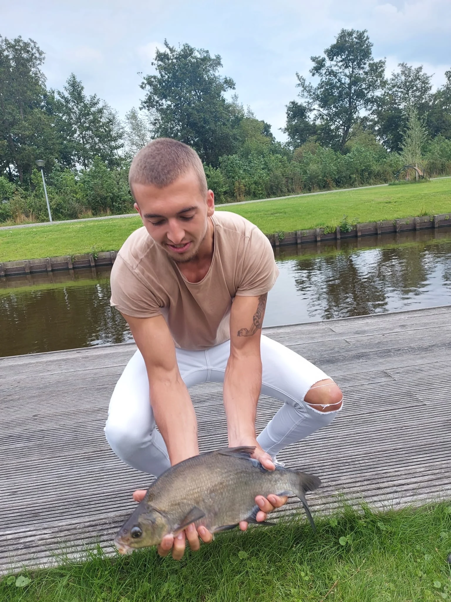 Wytse Punter met een brasem op een houten vlonder langs een Nederlands kanaal