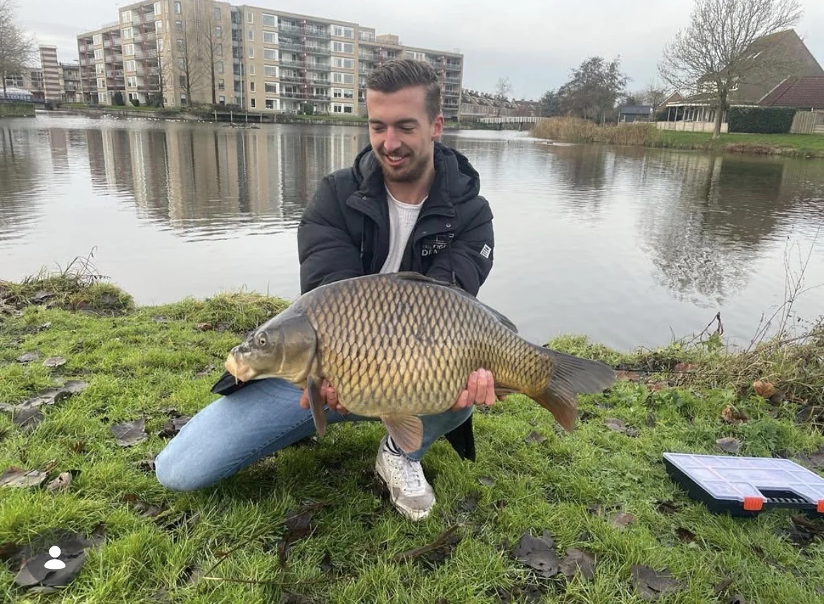 Wytse Punter met een karper langs een Nederlands stadskanaal, flatgebouwen op de achtergrond