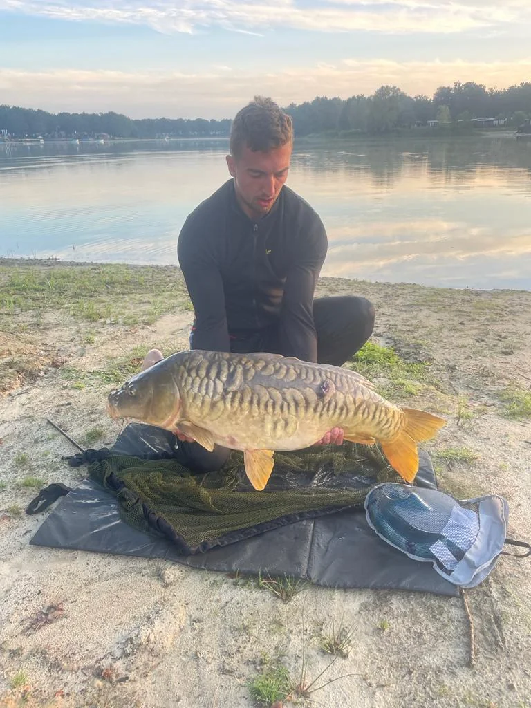 Wytse Punter met een grote spiegelkarper bij zonsopkomst aan een Nederlands meer