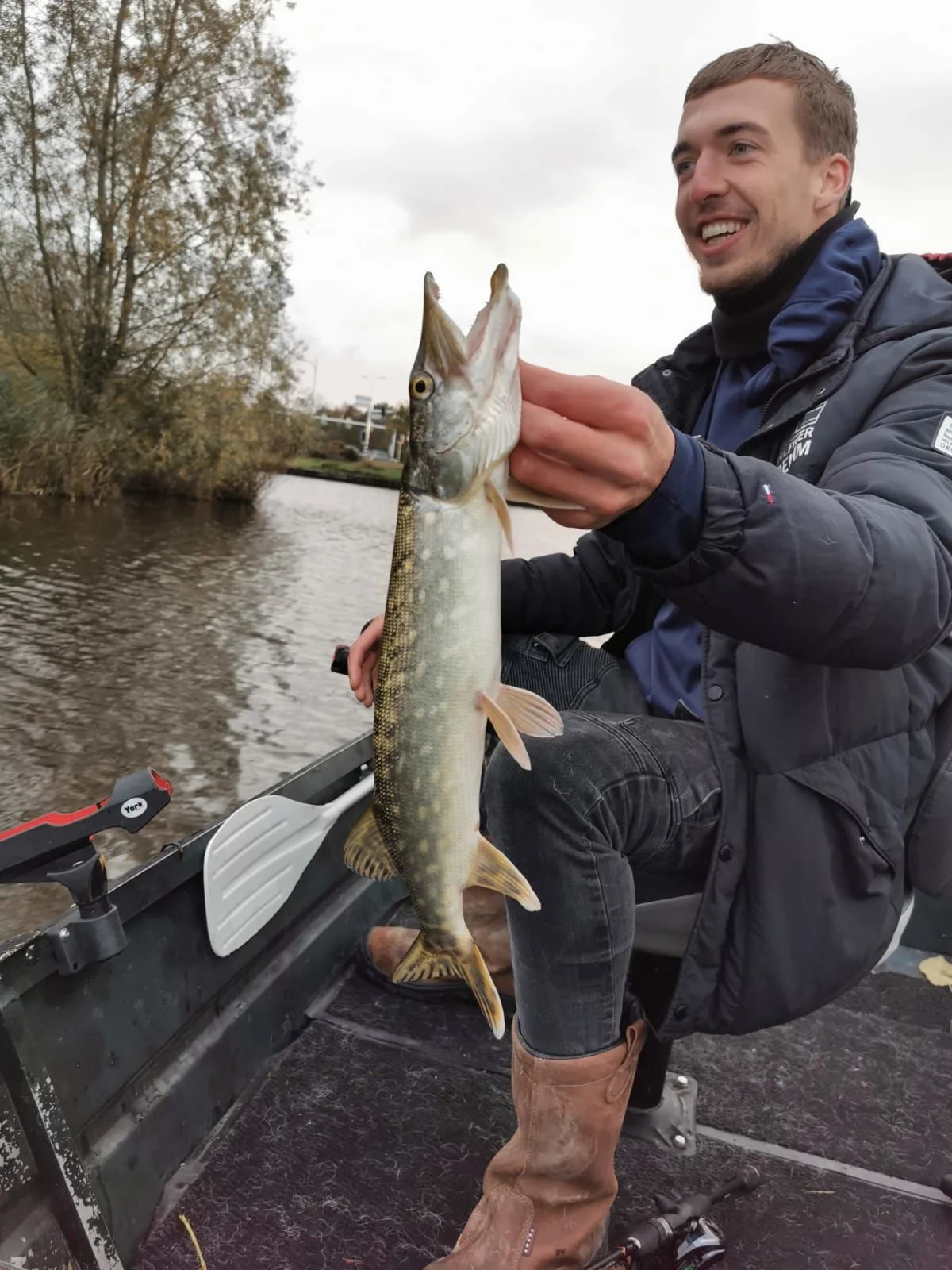 Wytse Punter met een snoek vanaf een klein bootje op een Nederlands kanaal in de herfst