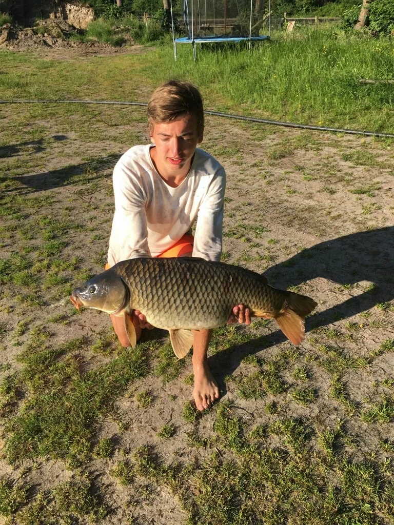 Tienjarige Wytse Punter met een karper in de tuin in de zomer